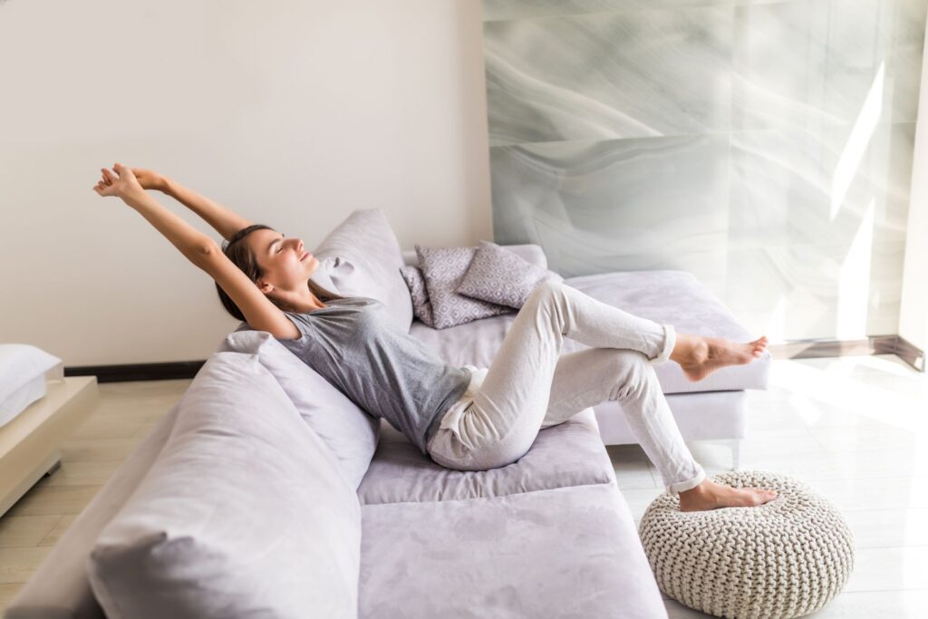 lachelnde junge frau entspannen sich liegend auf der couch
